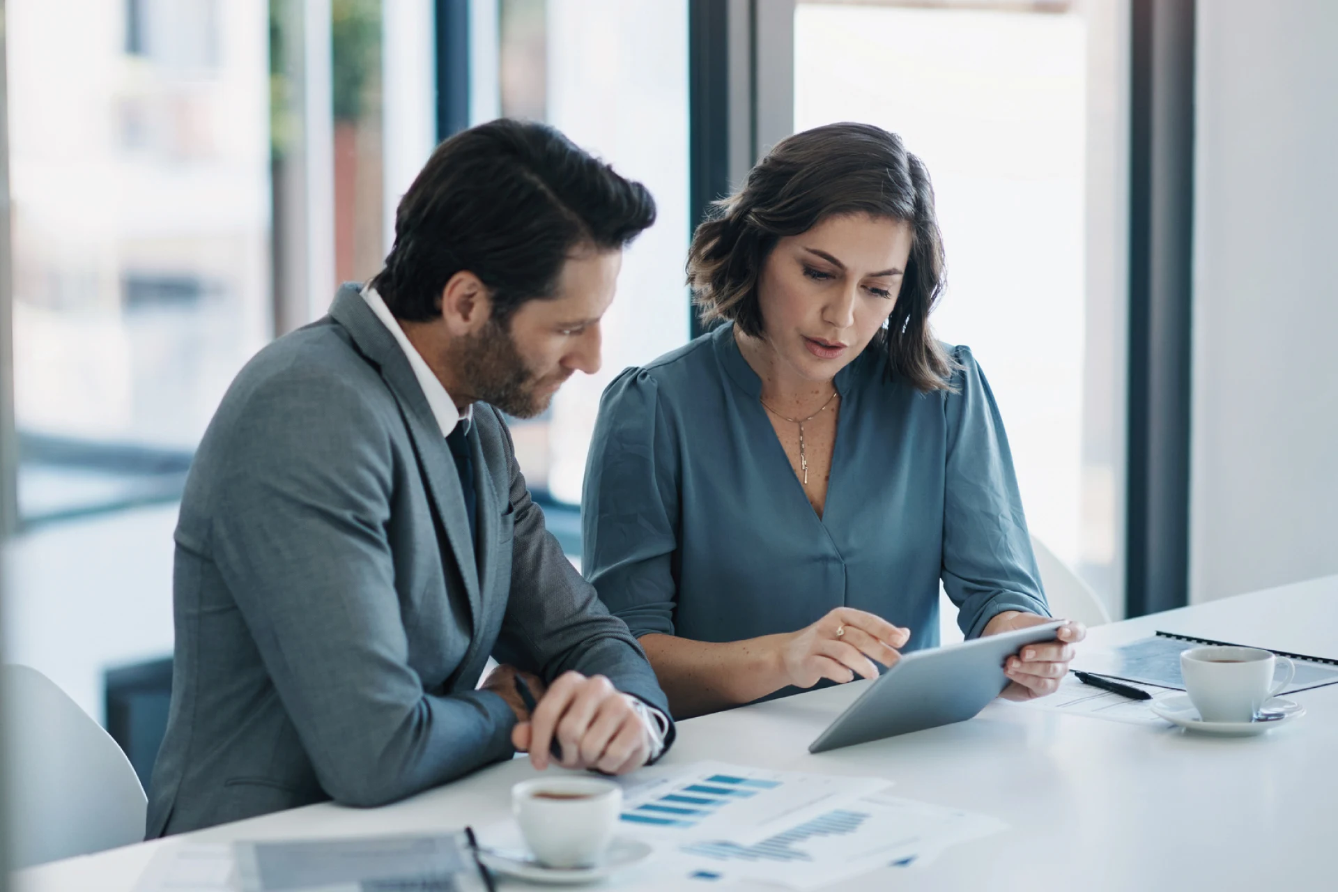 Two professionals discussing insights while reviewing data on a tablet.