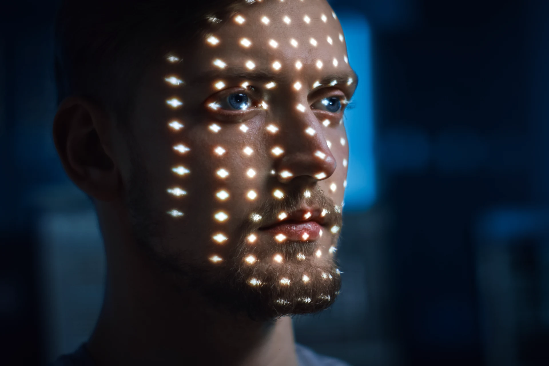 Close-up of a face illuminated with a grid of light patterns