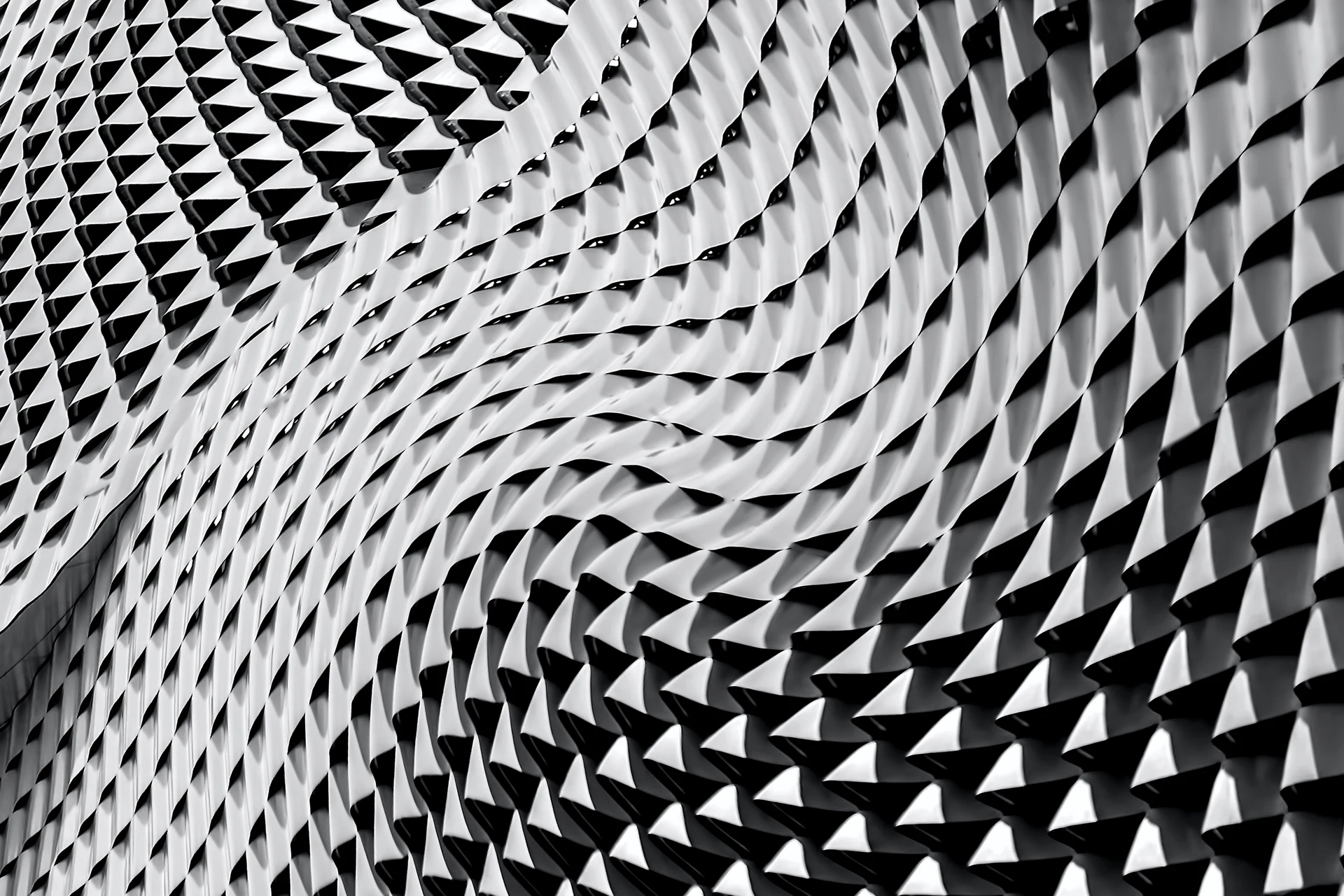 Undulating geometric facade made of repeating triangular panels.