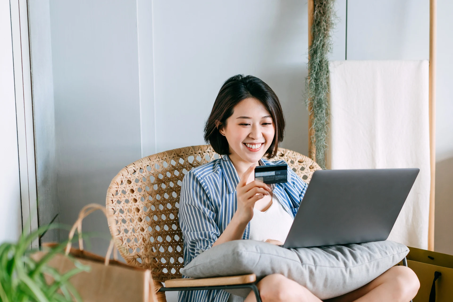 Person holding a credit card while using a laptop at home.