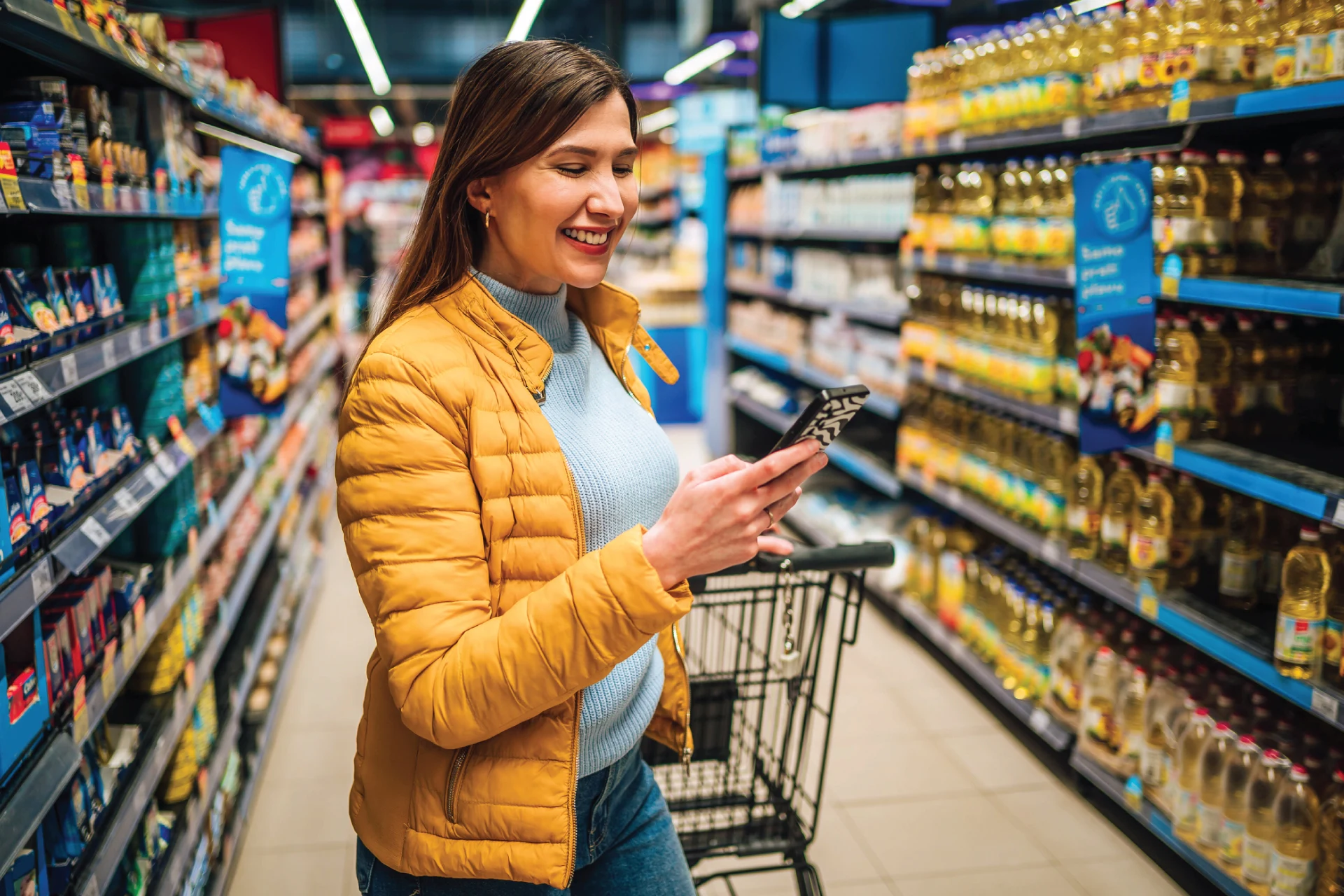 Person using a smartphone while shopping in a grocery store aisle.