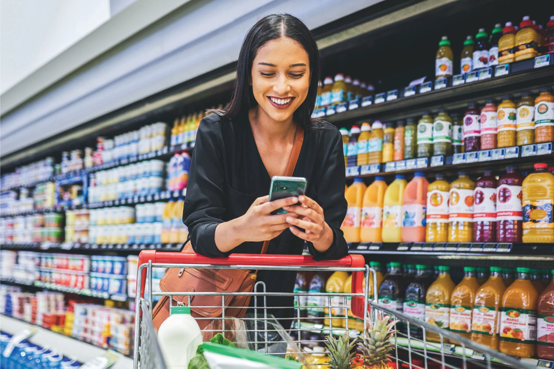 Woman using a smartphone while shopping in a grocery store aisle