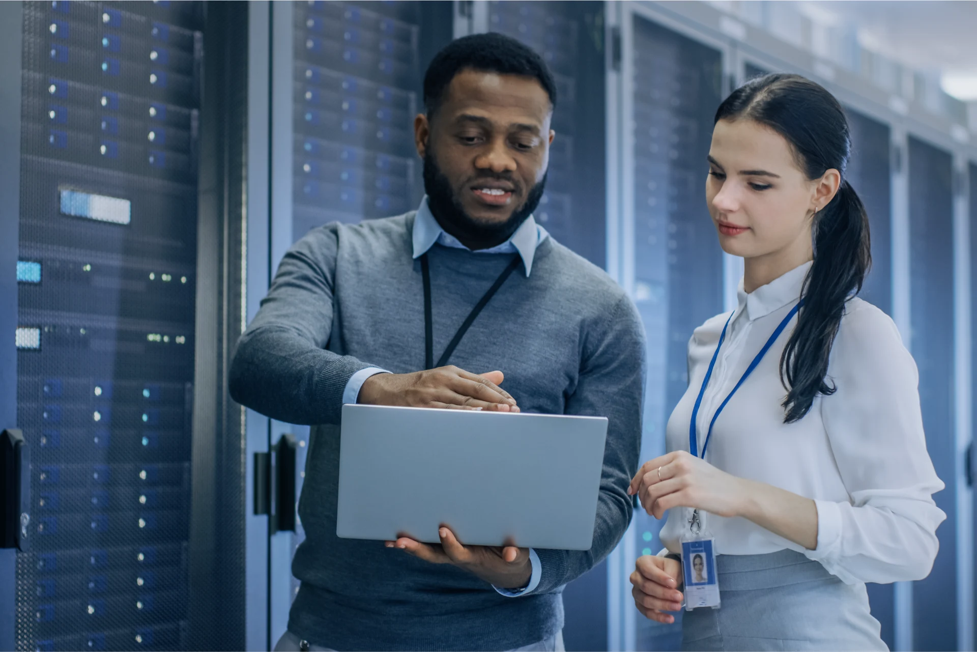 Two professionals discussing cloud solutions while using a laptop.