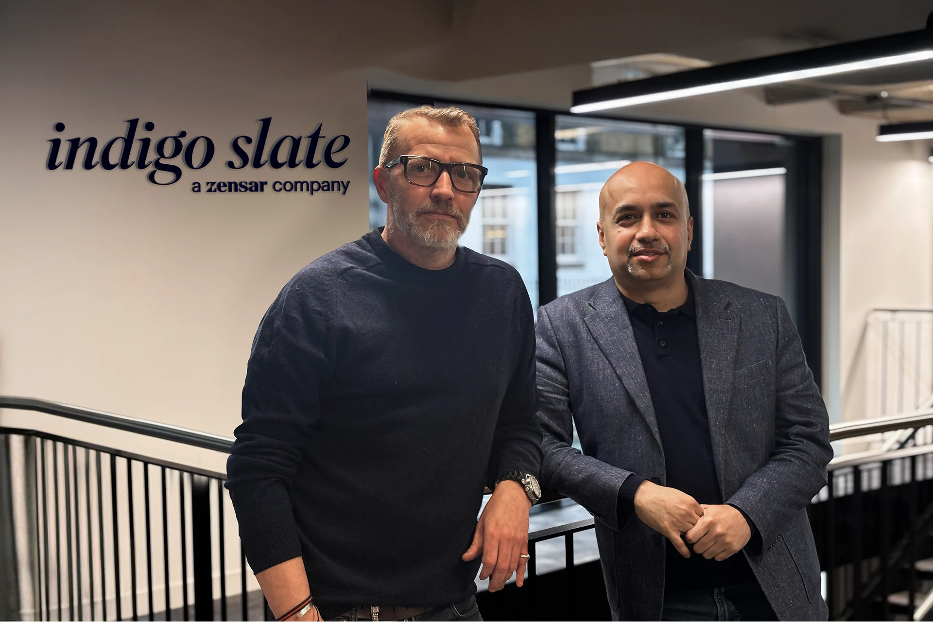 Professionals standing next to Indigo Slate office sign in London UK