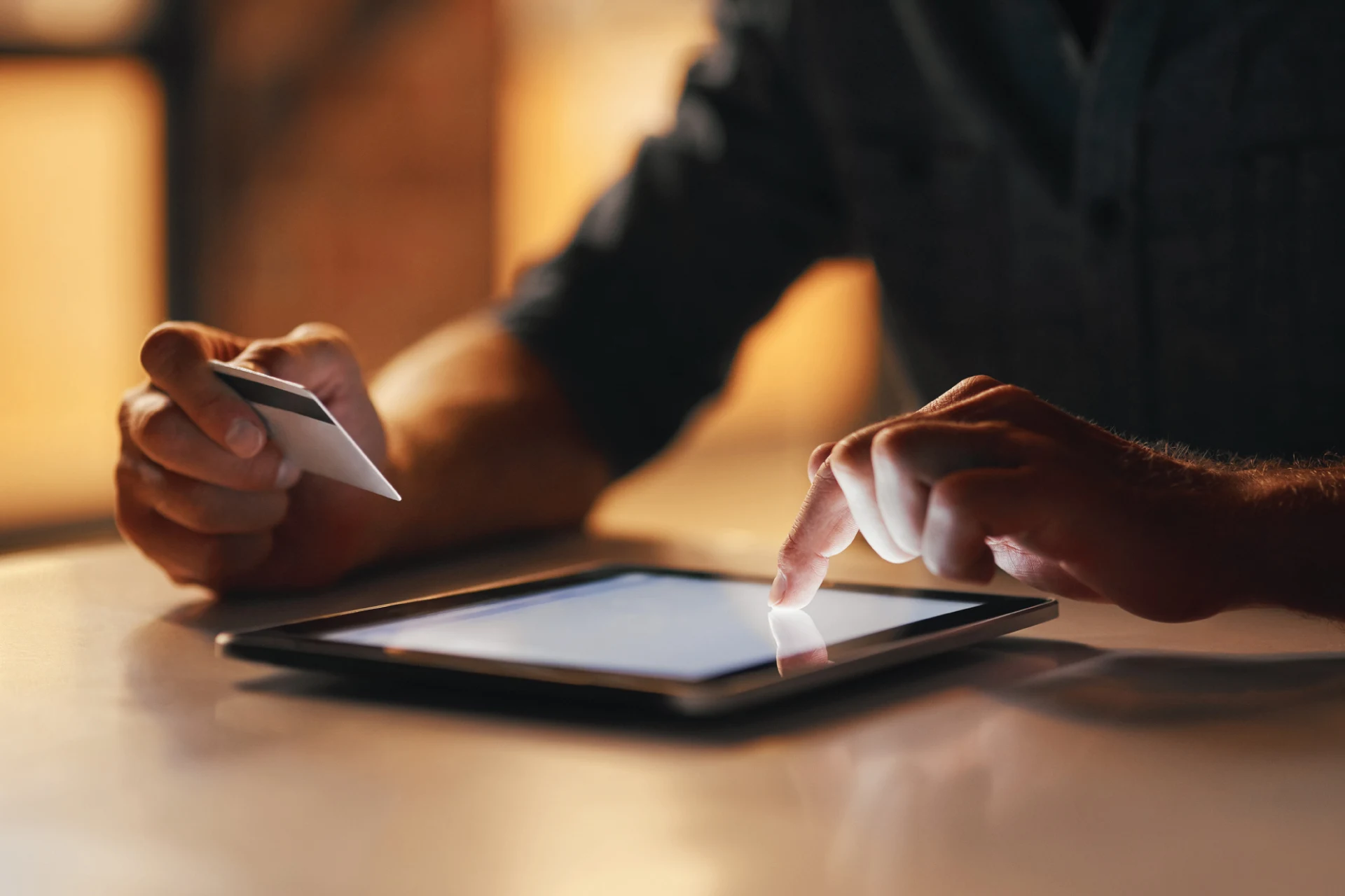 Person using a tablet and holding a credit card for a fintech transaction