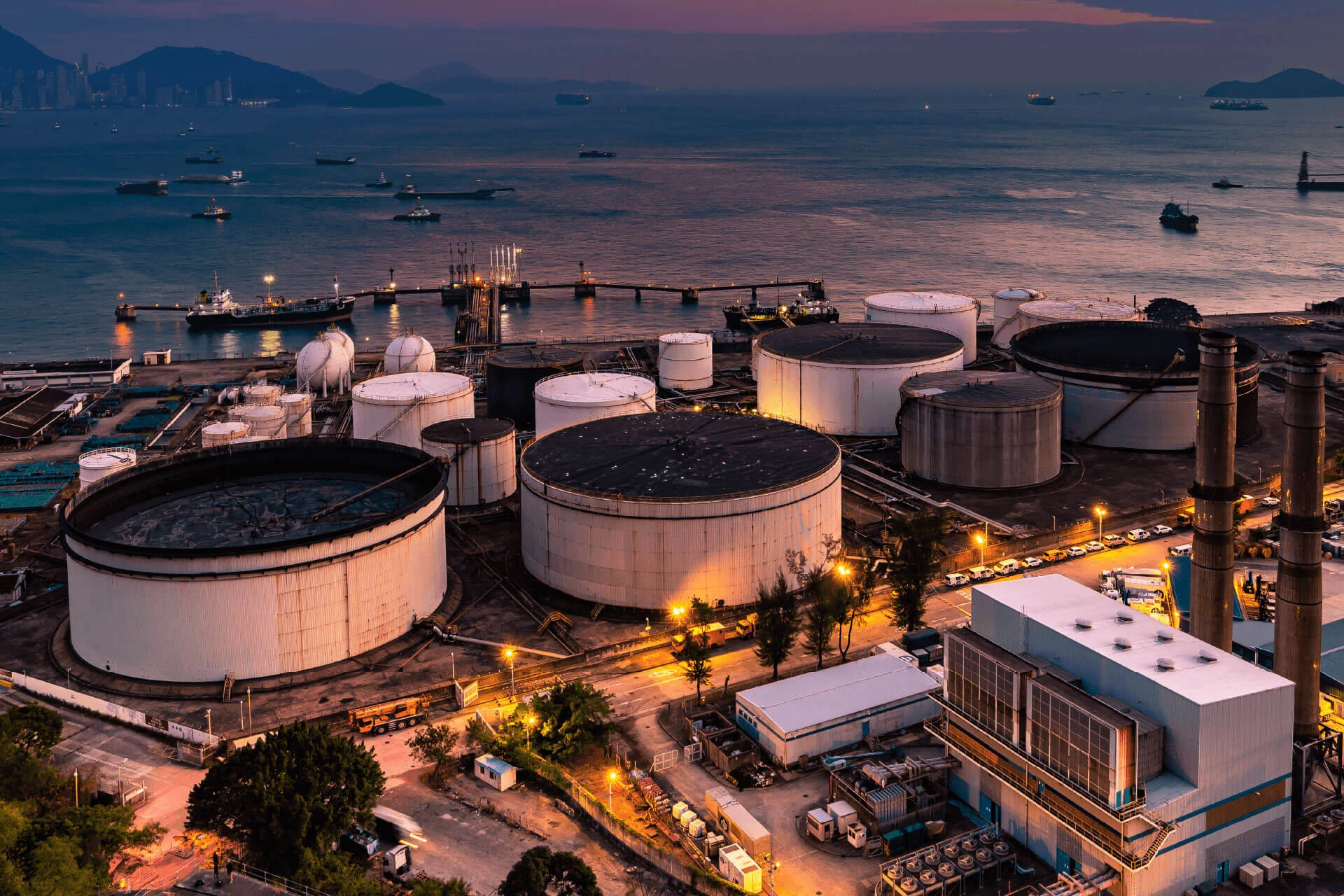 Oil and gas storage tanks and facilities at night near the water