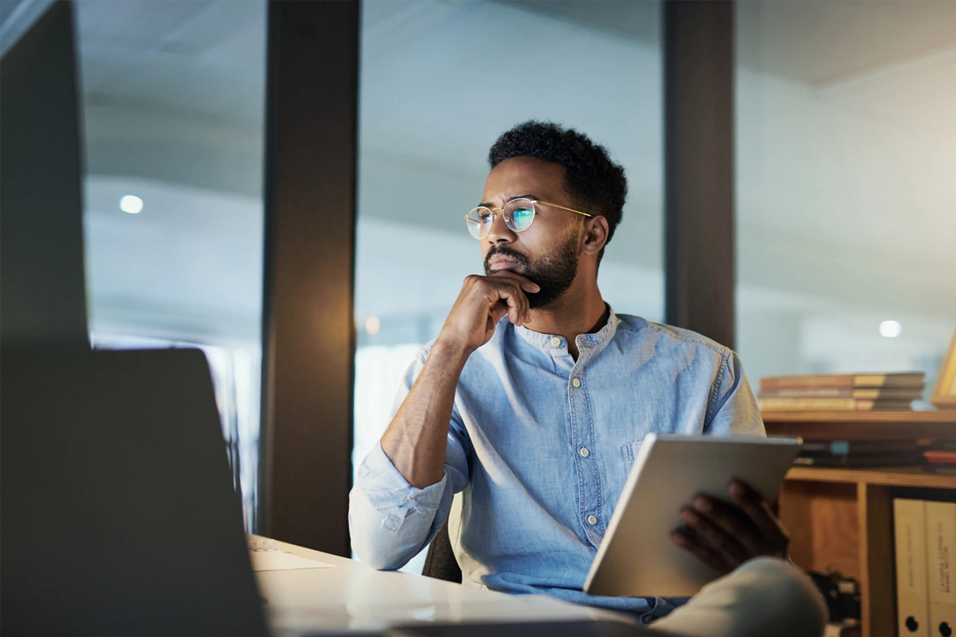 Professional pondering while holding a tablet during work hours