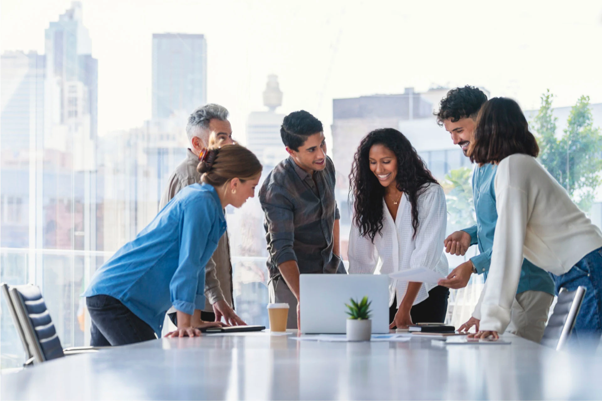 Group collaborating at a table with a laptop in a modern office setting