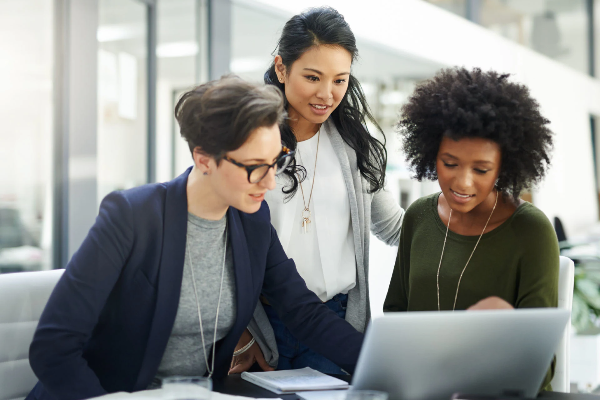 Three professionals collaborating on a laptop in an office setting