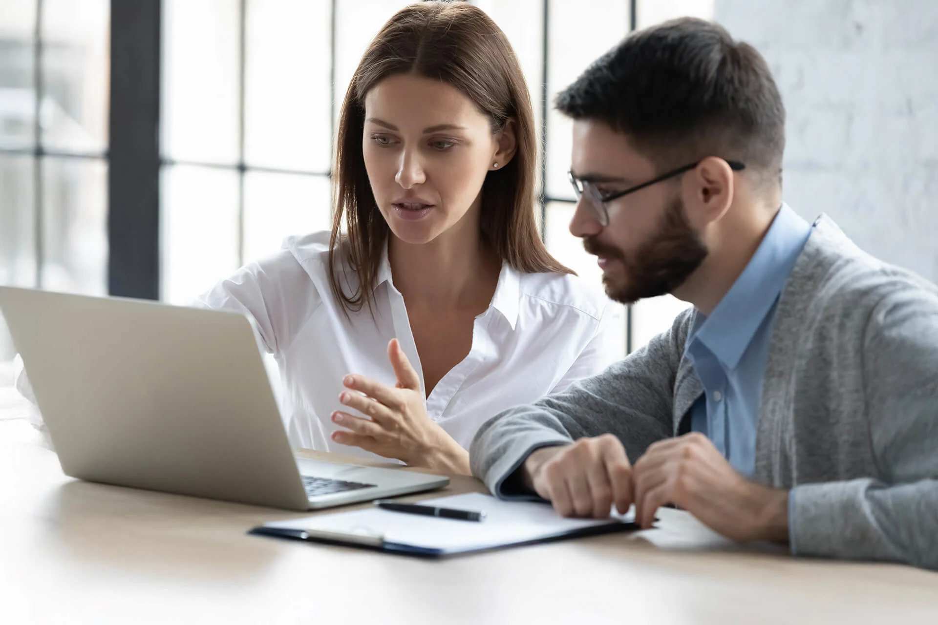 Two professionals discussing data insights using a laptop in an office setting