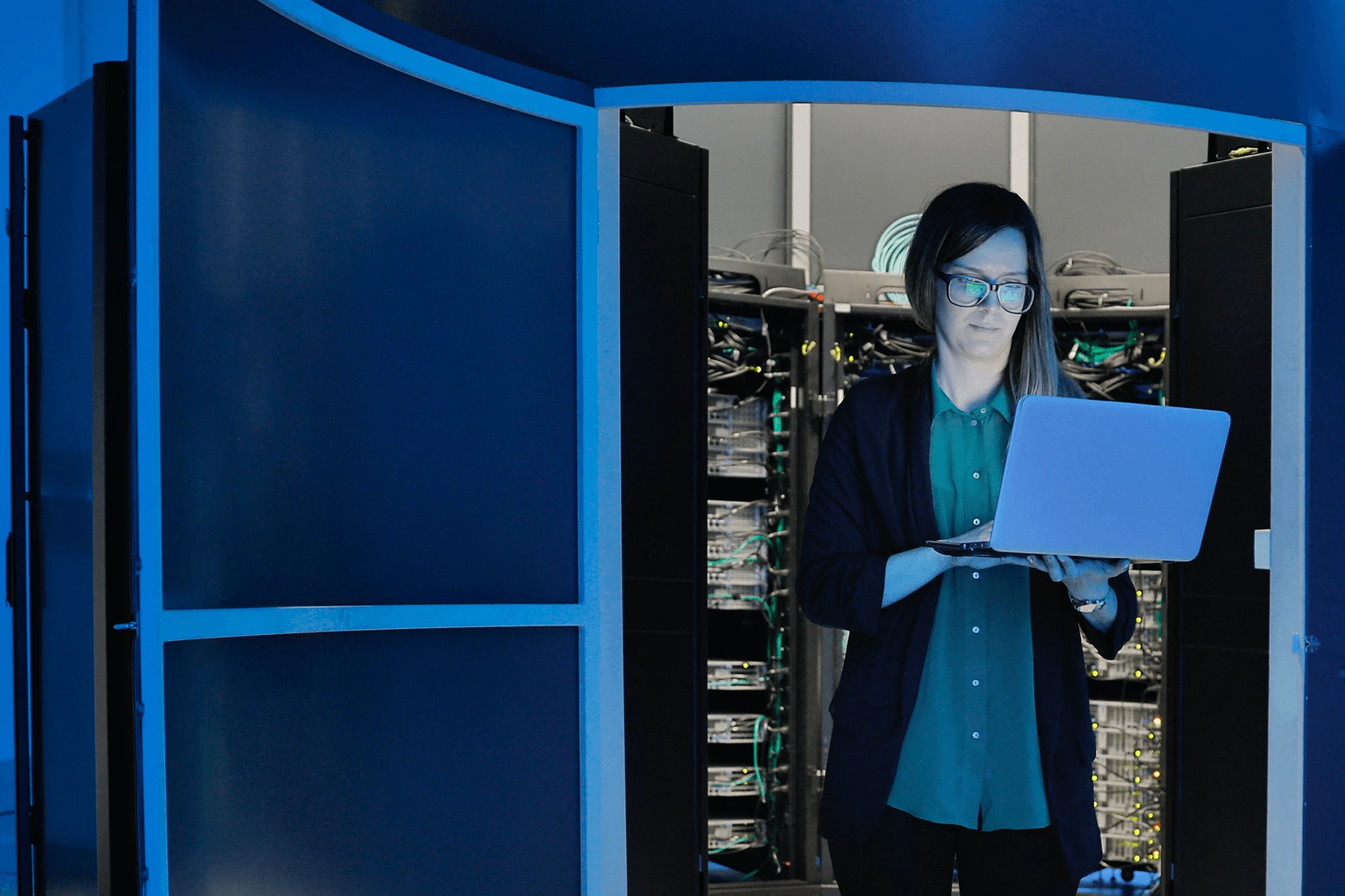 Professional using a laptop in a server room for cybersecurity purposes.