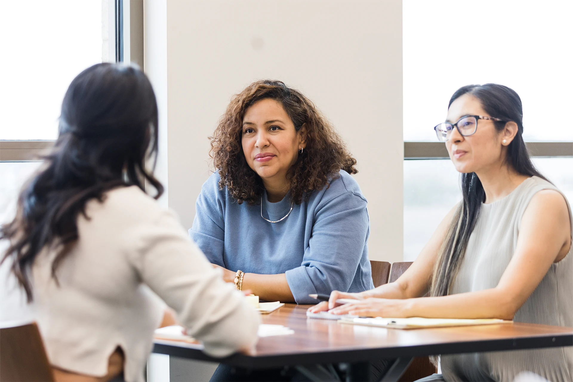 Three professionals engaged in discussion during a meeting about SAP Joule.