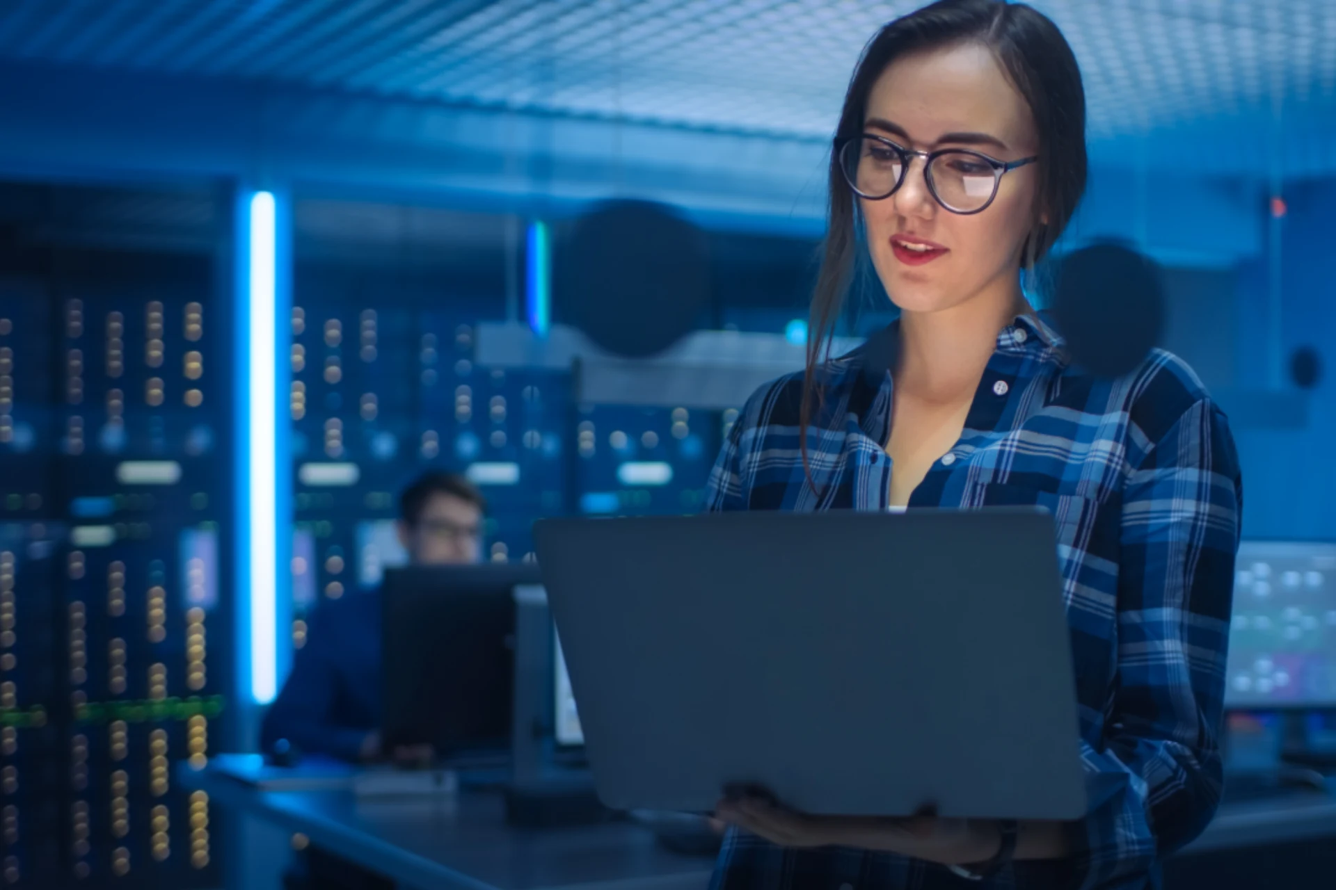 Woman holding a laptop in a cybersecurity operations center.