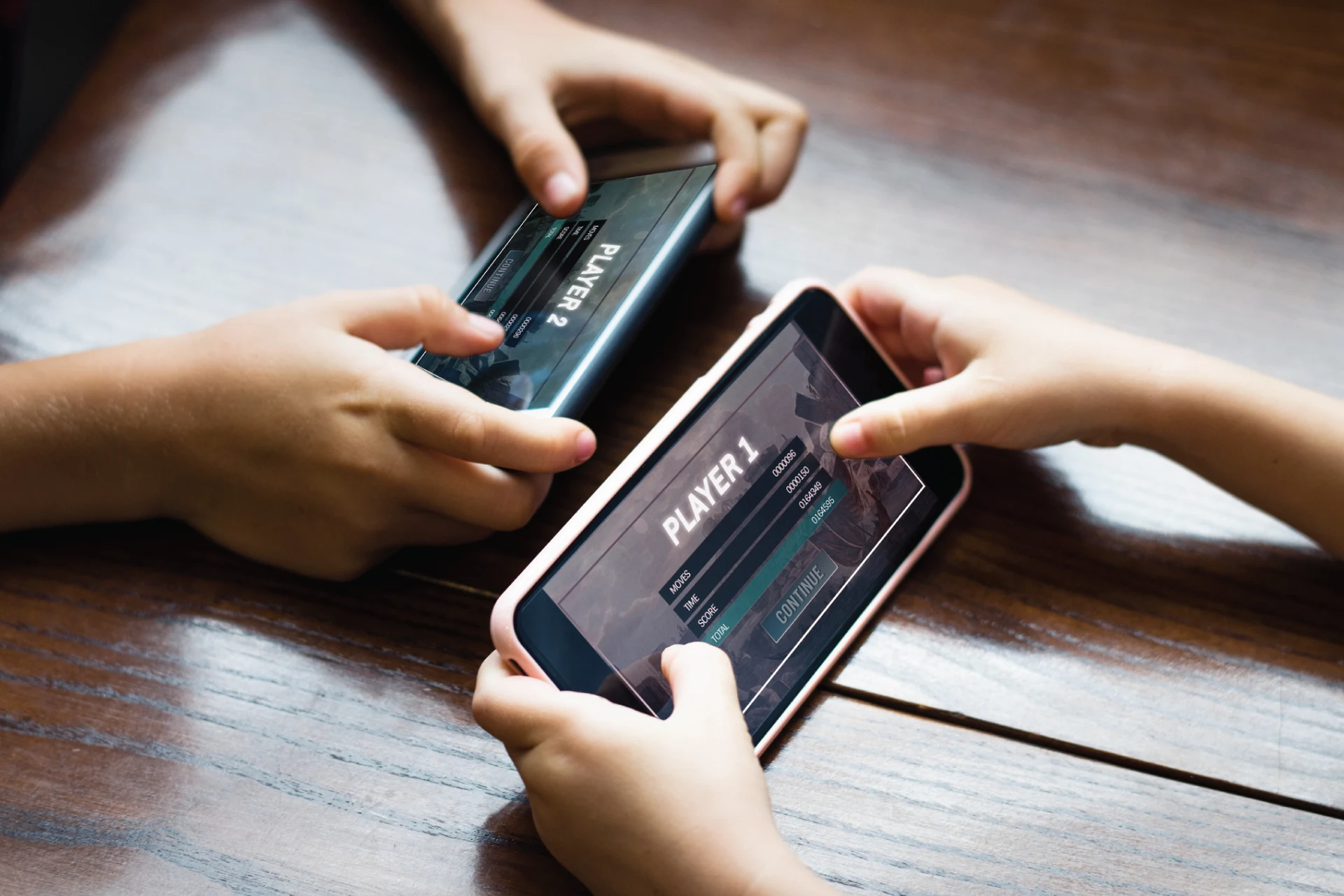Two children playing a mobile game, showing Player 1 and Player 2 screens.