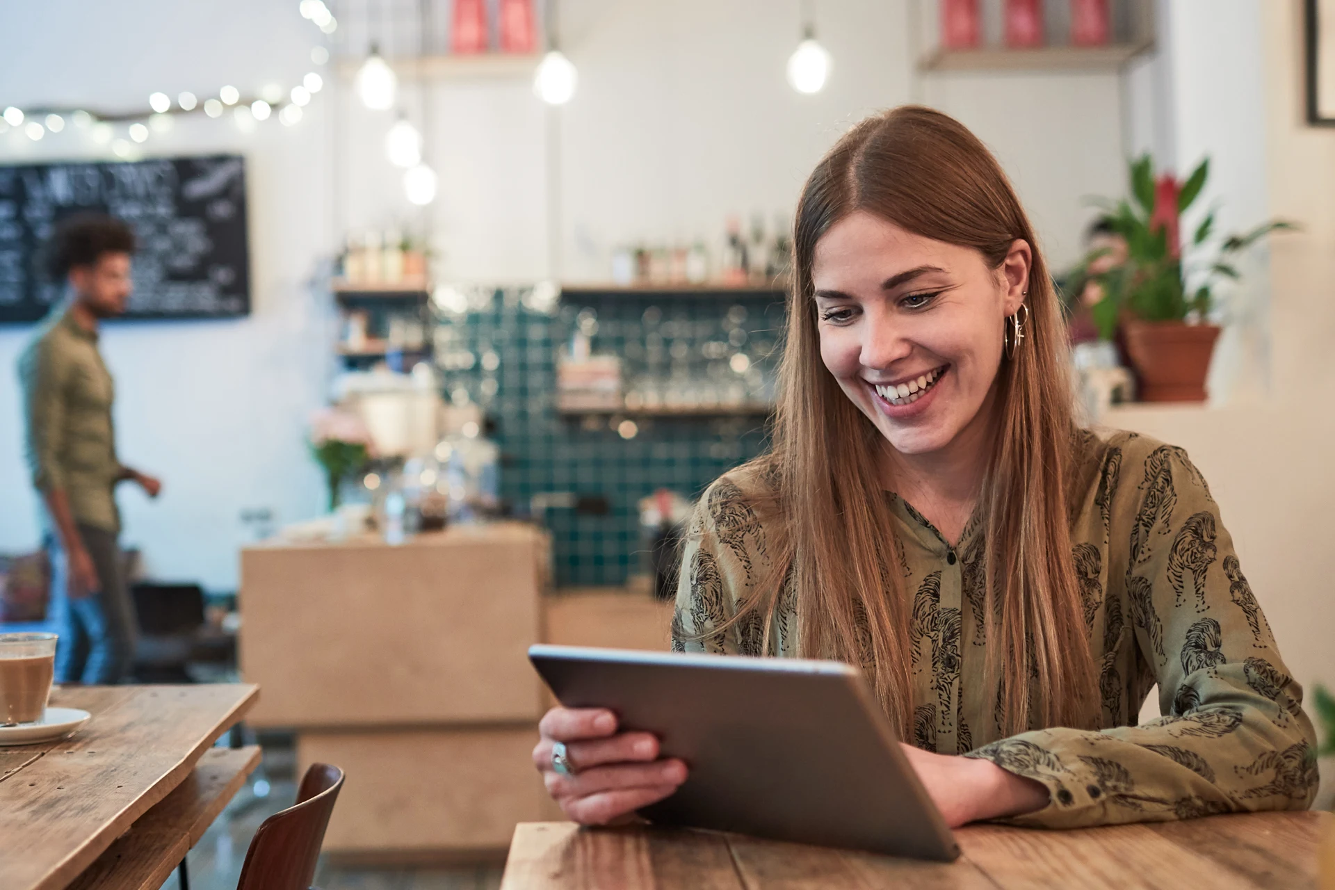 Woman using a tablet in a caf� as part of a hybrid cloud discussion