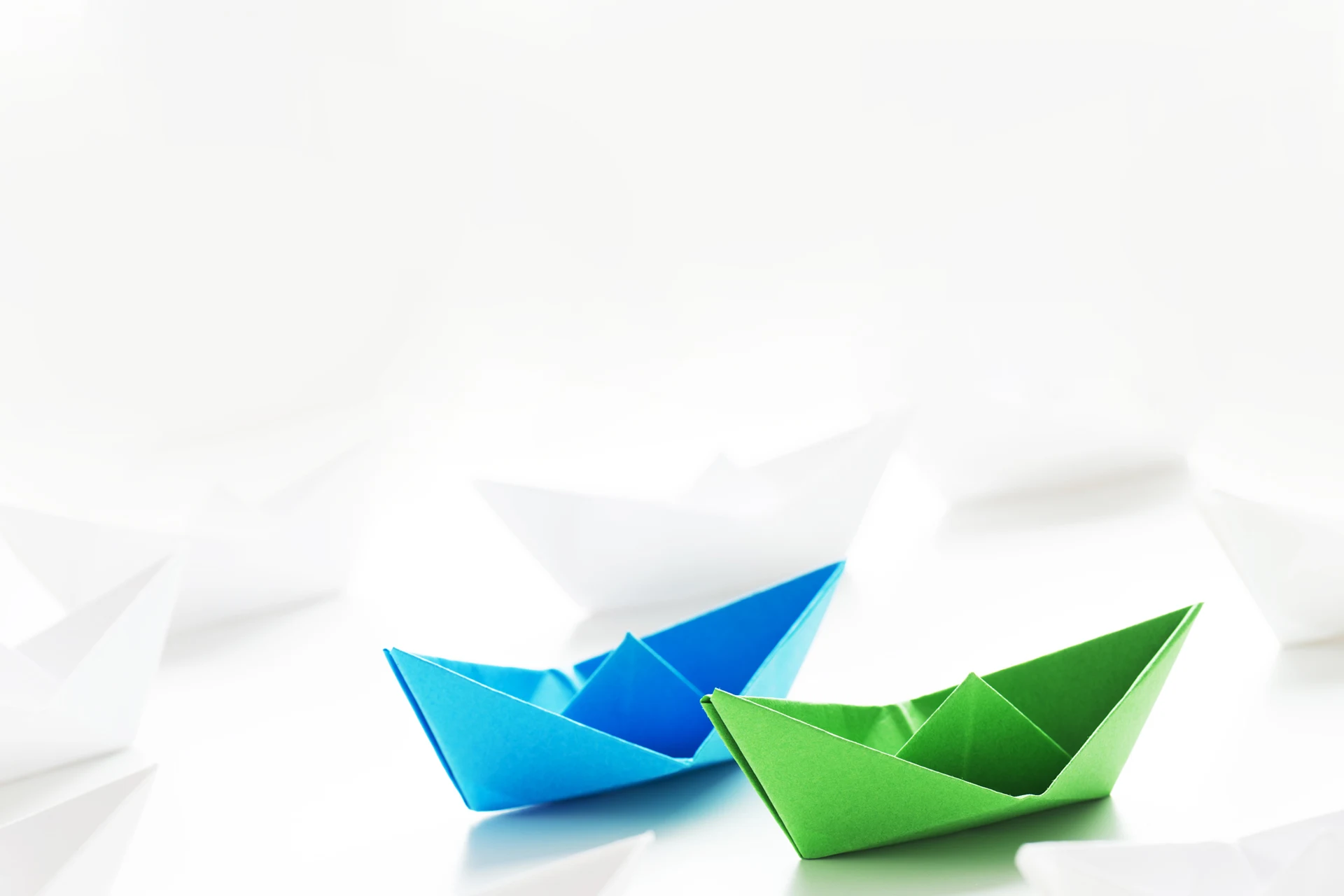 Colorful paper boats on a white surface representing marketing concepts