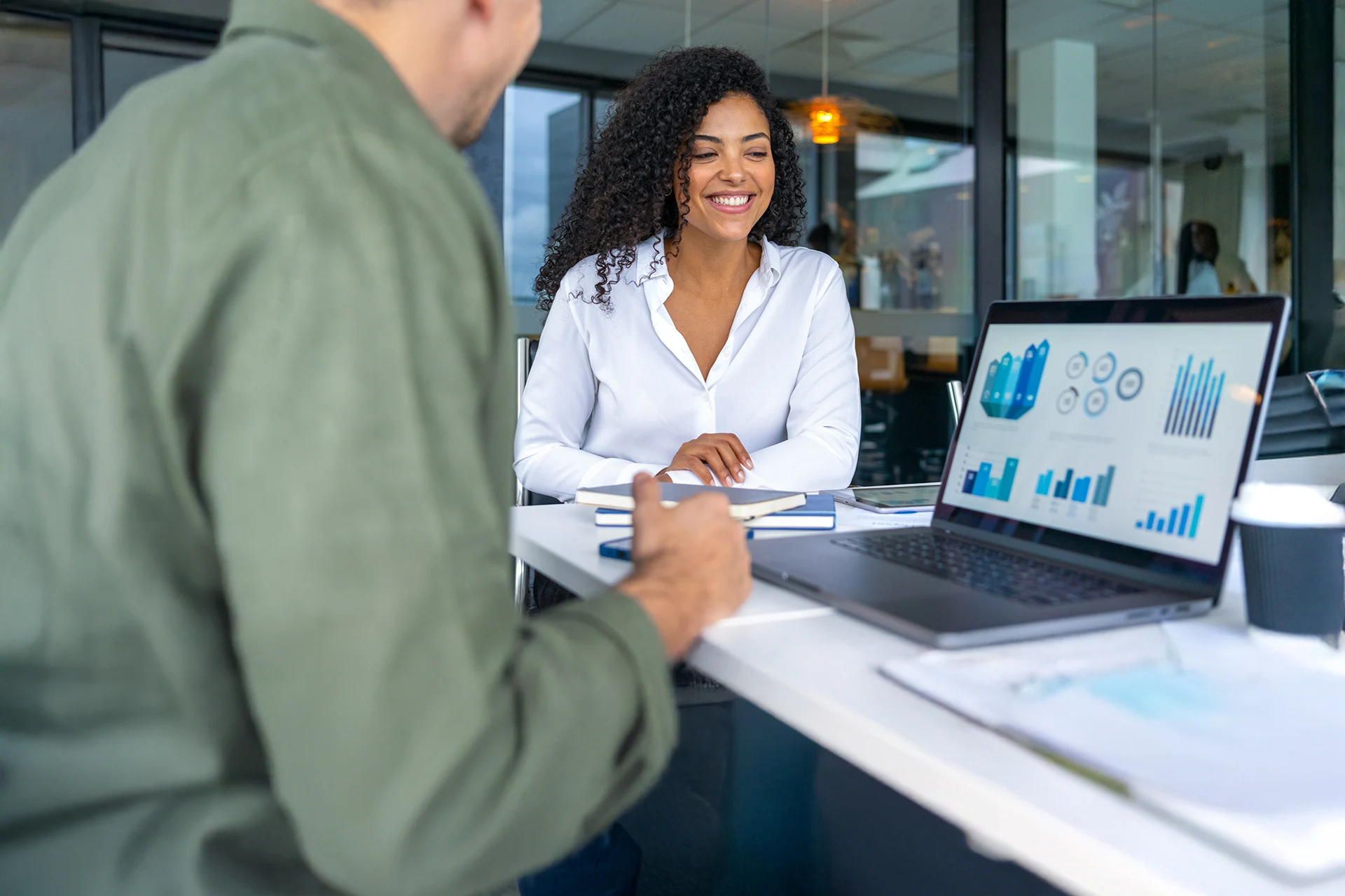 Two professionals engaged in a discussion over a laptop displaying data.