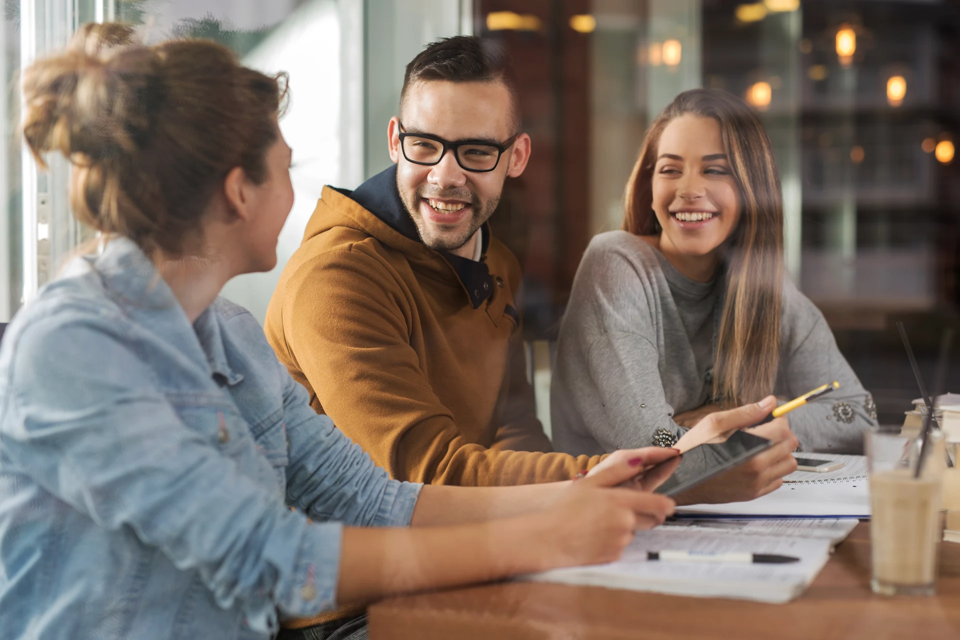 Three professionals engaged in discussion over devices in a cafe