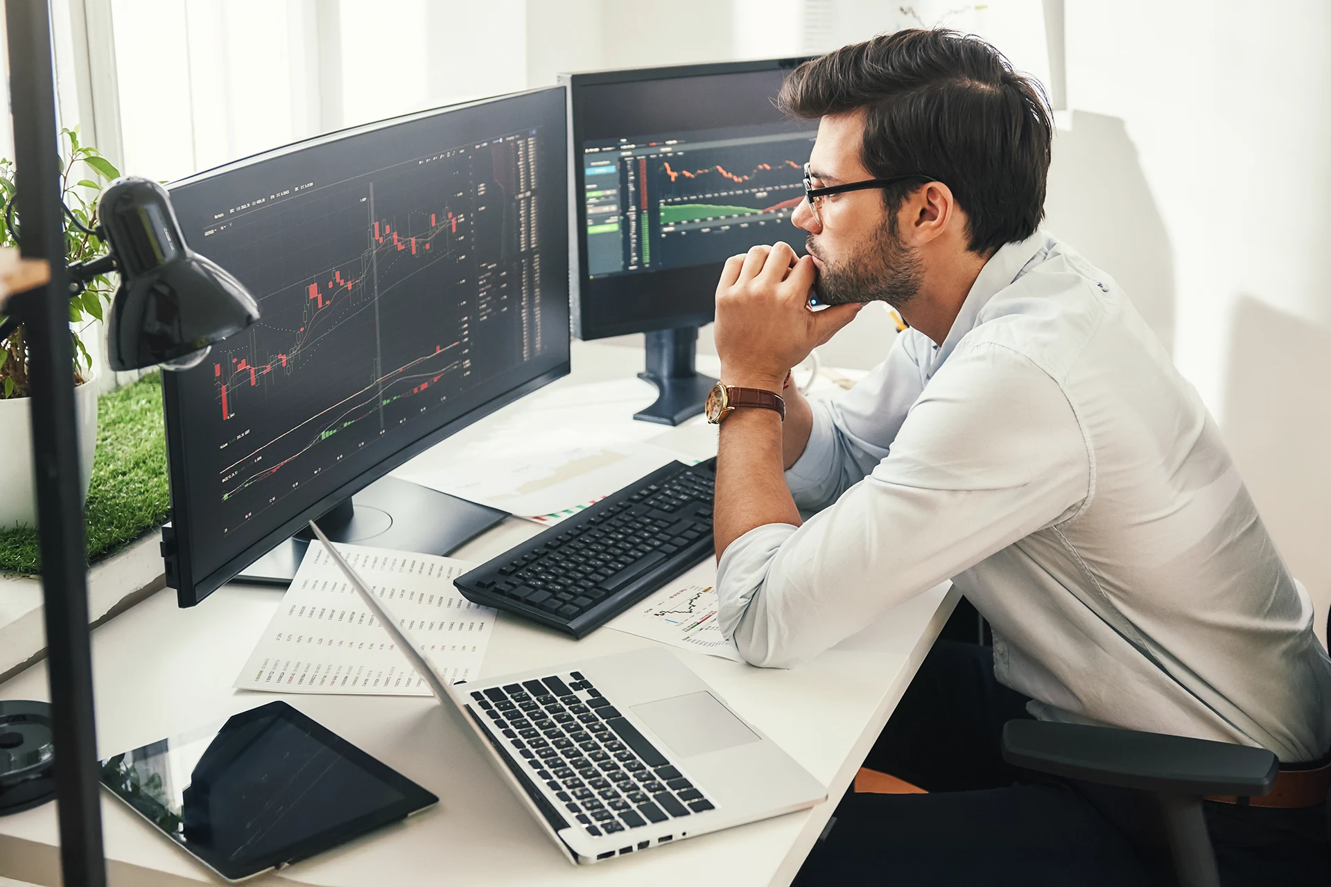 Professional analyzing data on multiple monitors in a modern office setup