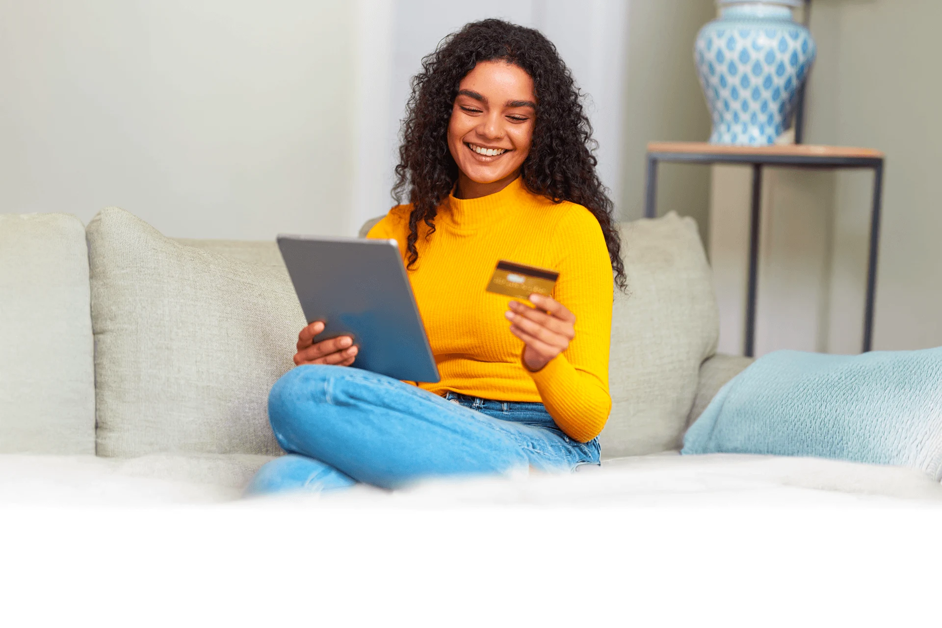 Woman using a tablet and holding a credit card at home