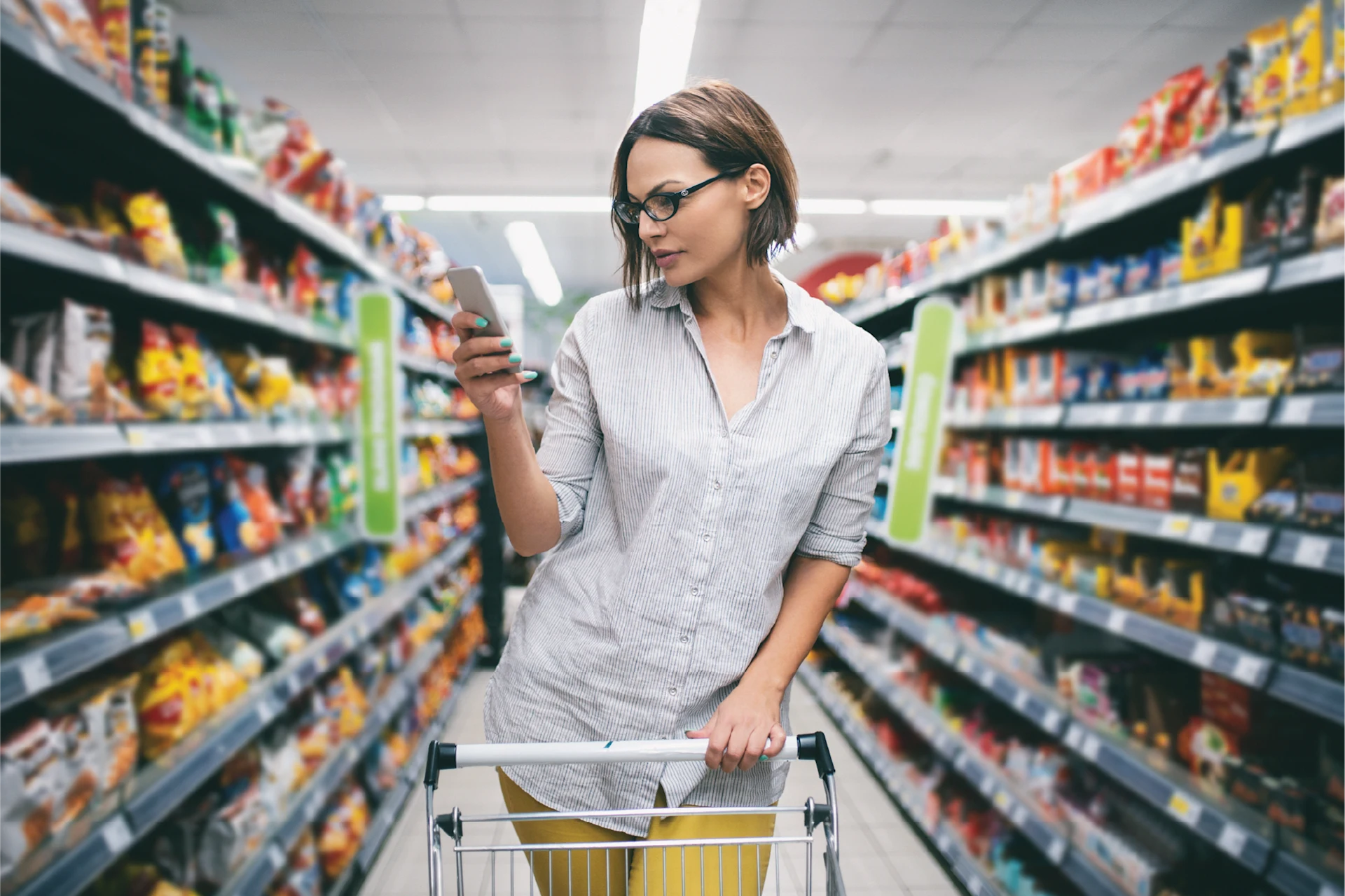 Shopper using a smartphone in a supermarket aisle