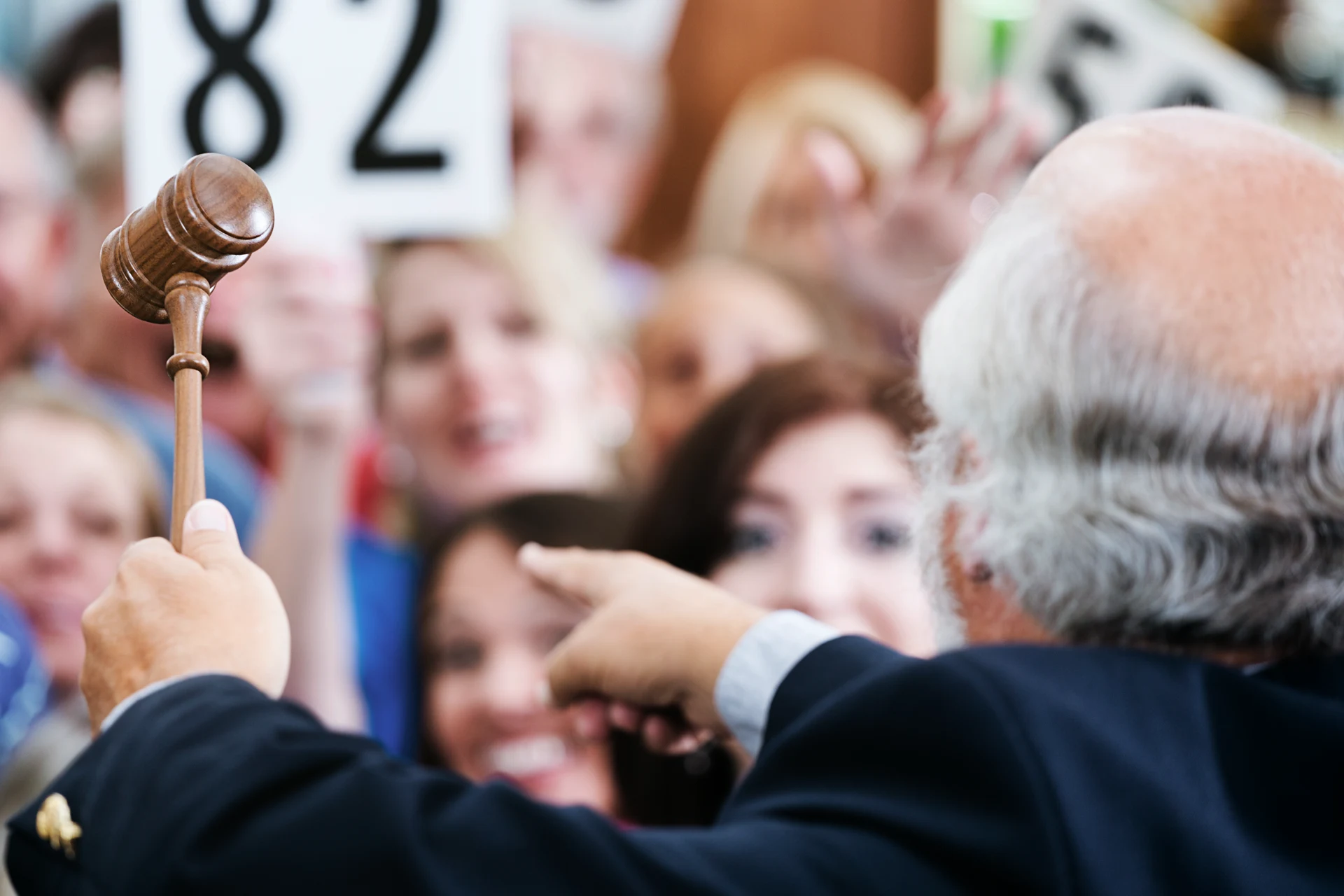Auctioneer raising a gavel amid an audience at an auction event