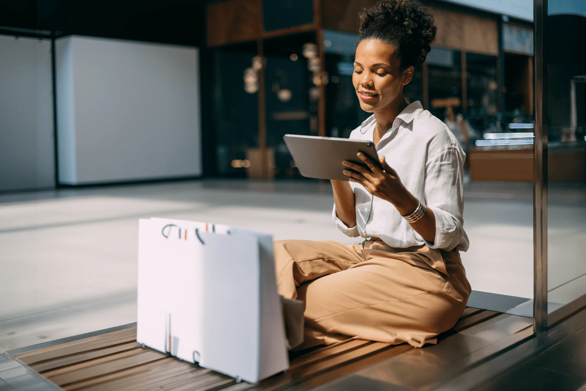 Person sitting cross-legged using a tablet in a modern space.