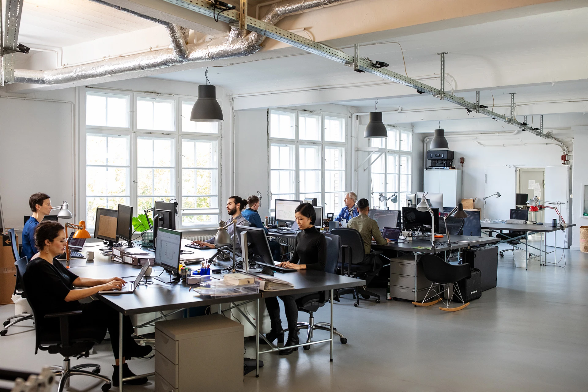 Employees collaborating in a modern office environment with computers.