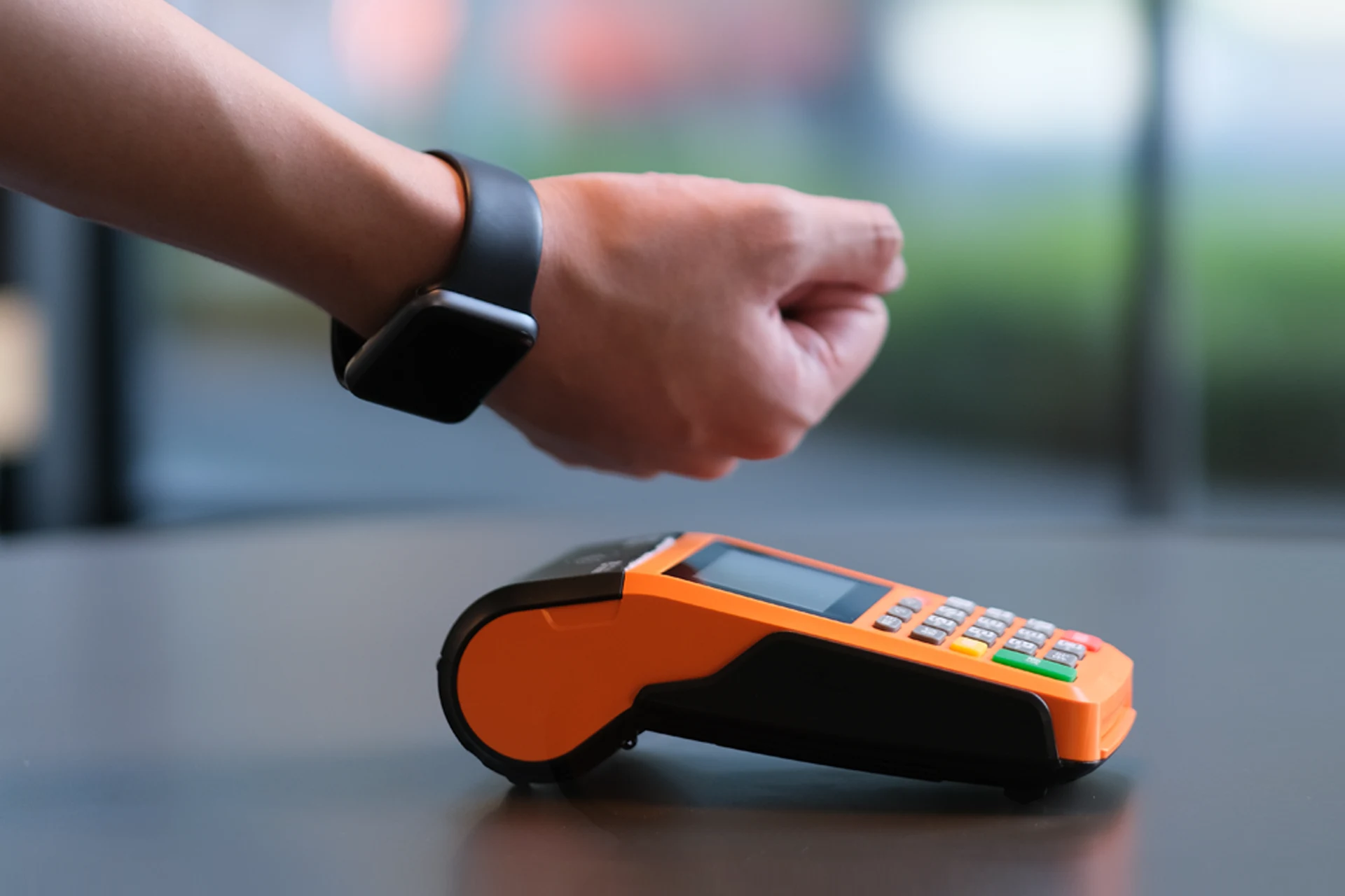 Hand using a contactless payment smartwatch near a payment terminal