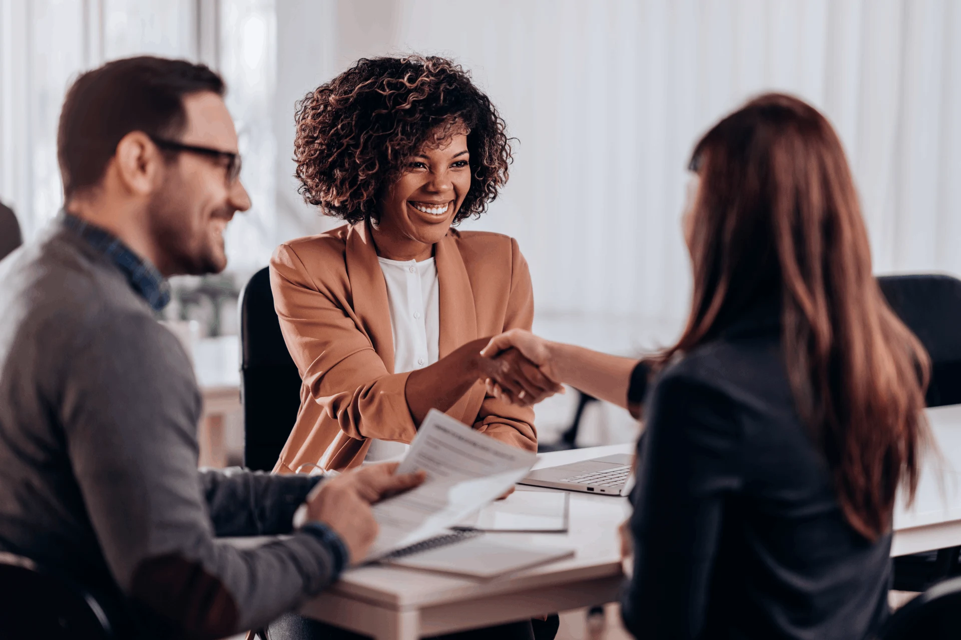 Two professionals shaking hands during a business meeting in an office.