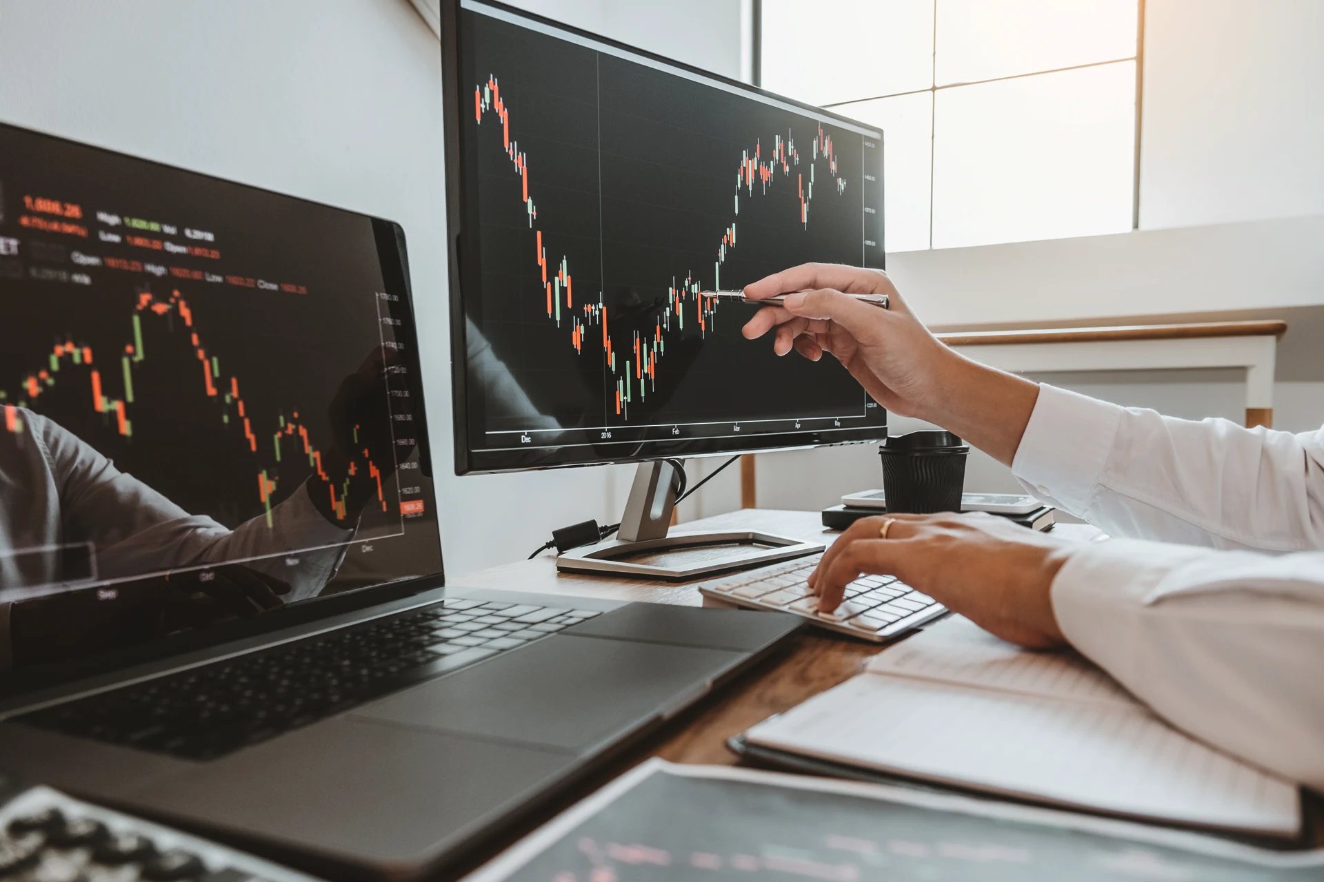 A professional analyzing sales data on dual monitors with a laptop.