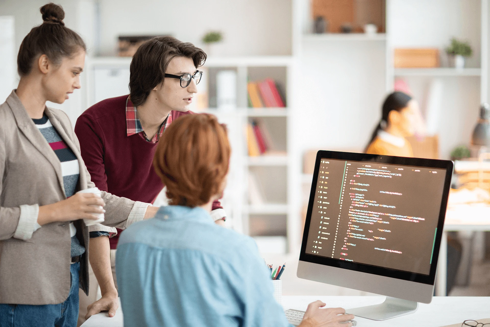 Team collaborating around a computer displaying code in an office setting