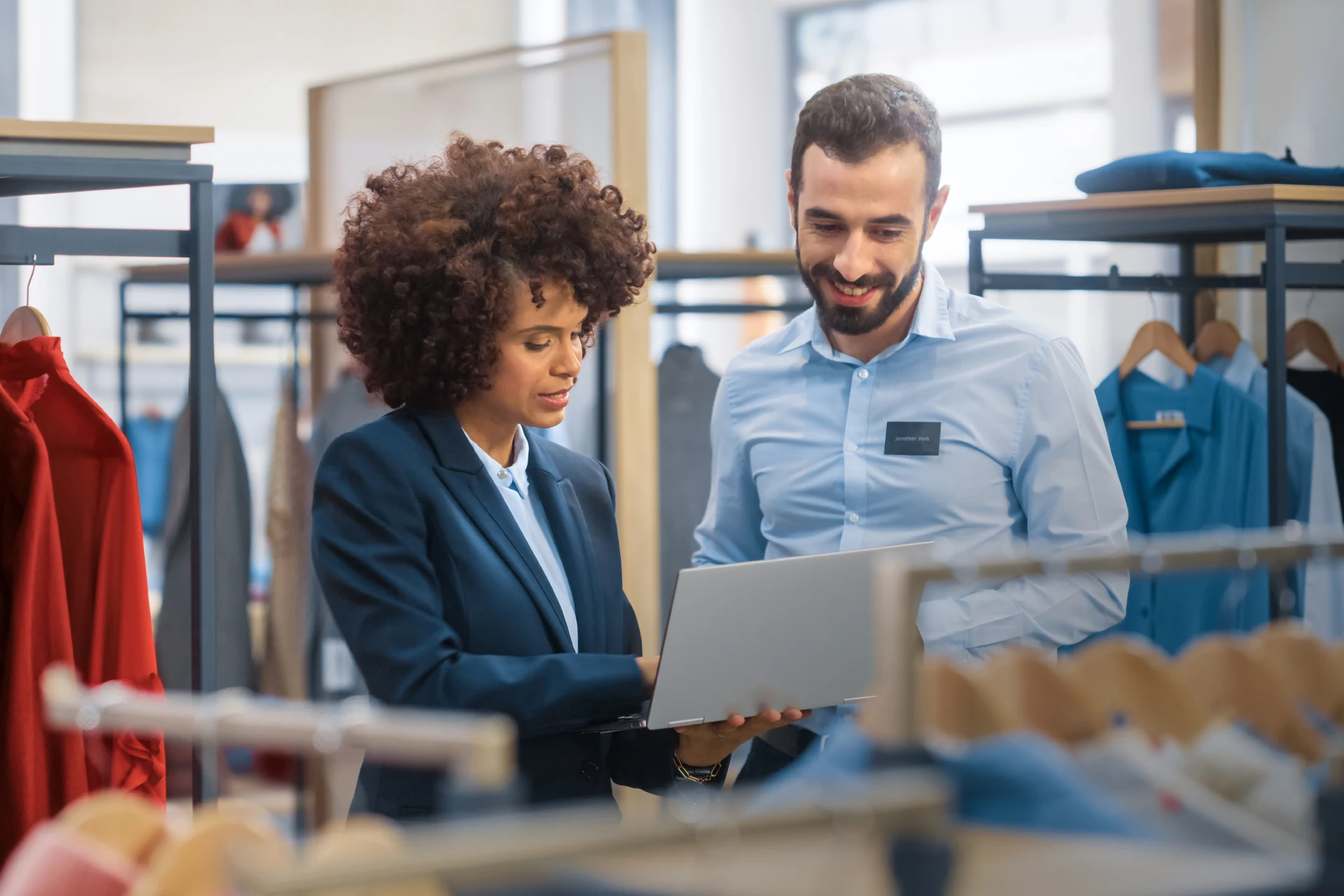 Two professionals discussing a laptop in a retail clothing store