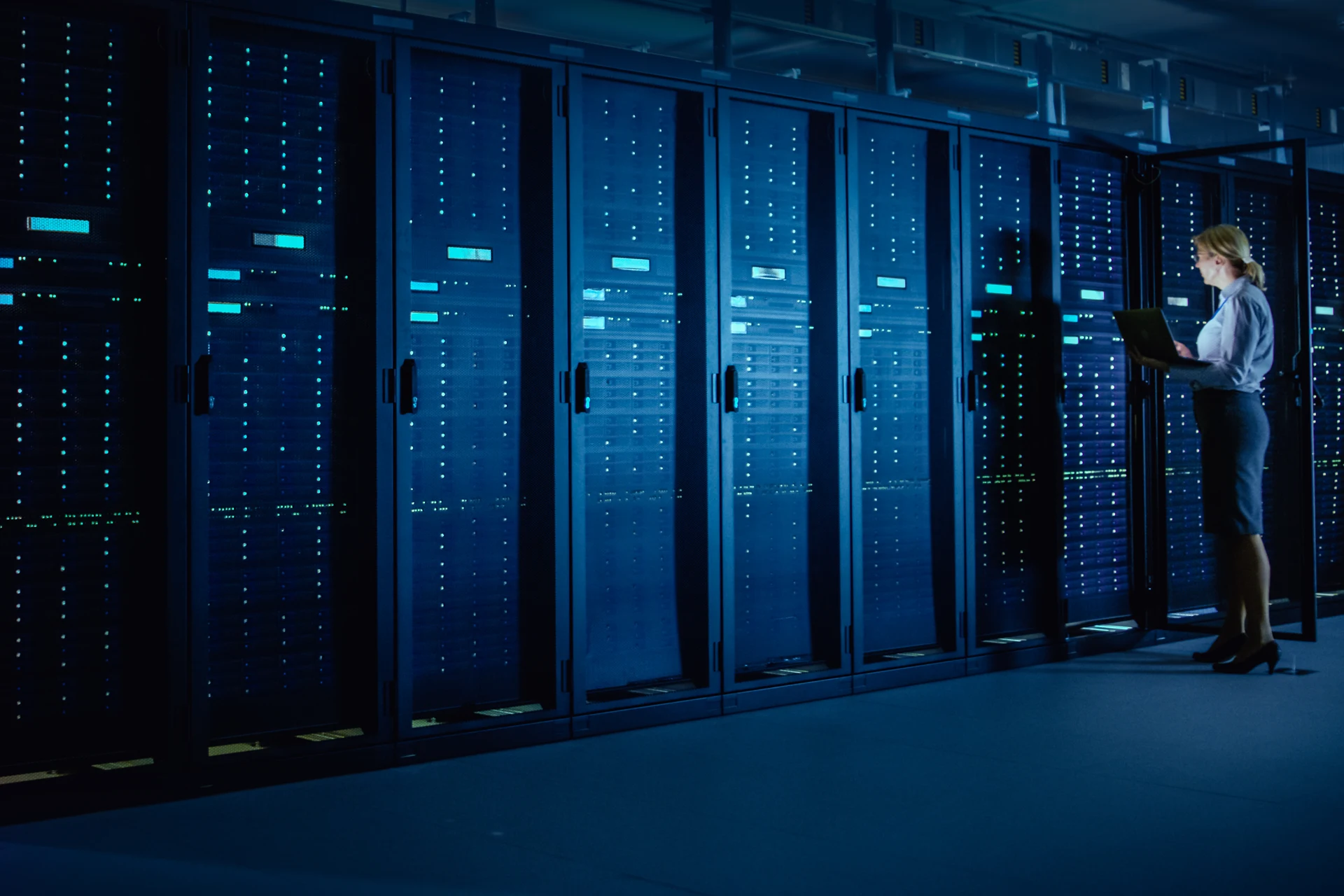 Professional reviewing data on a laptop in a server room