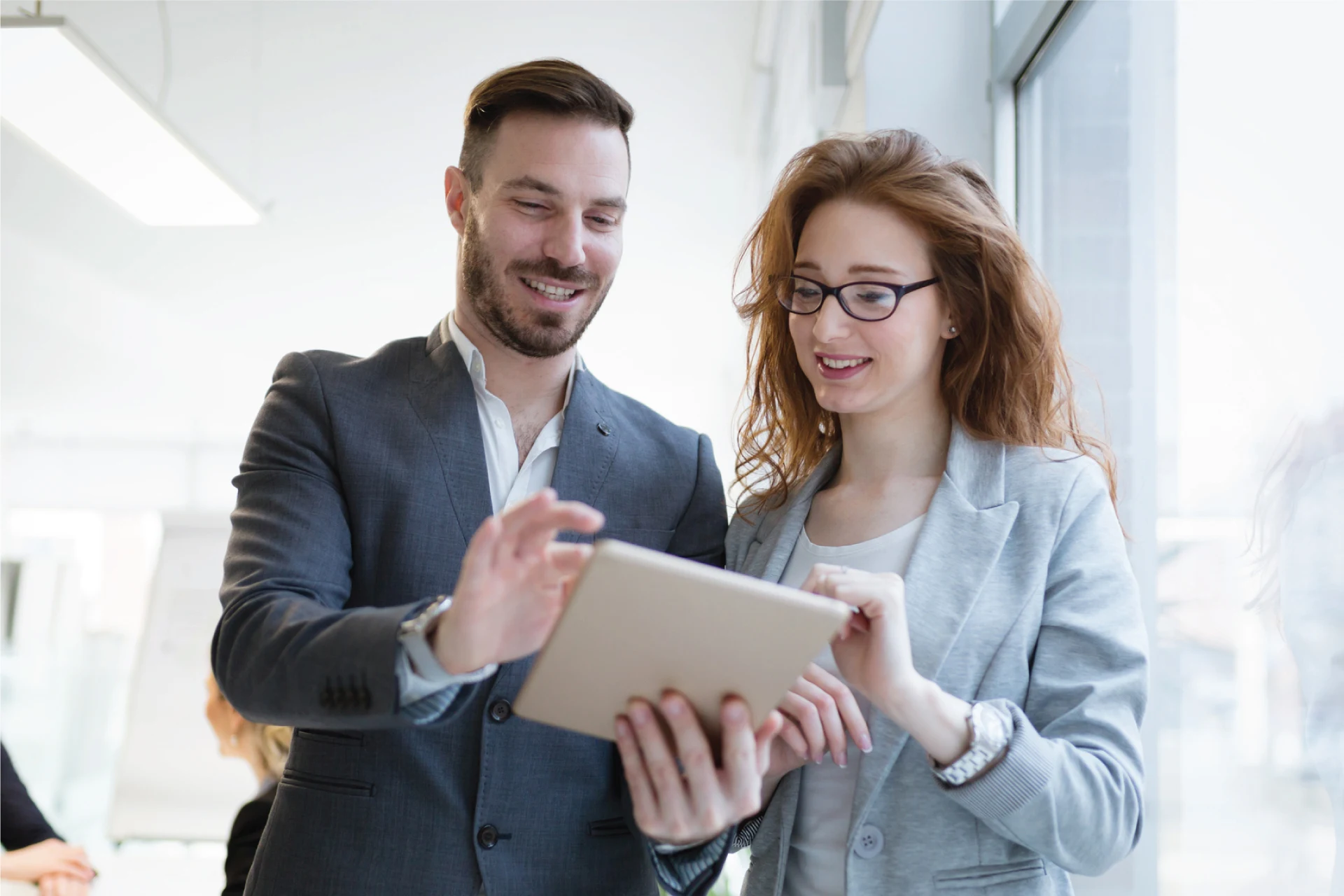 Two professionals discussing data on a tablet in a bright office