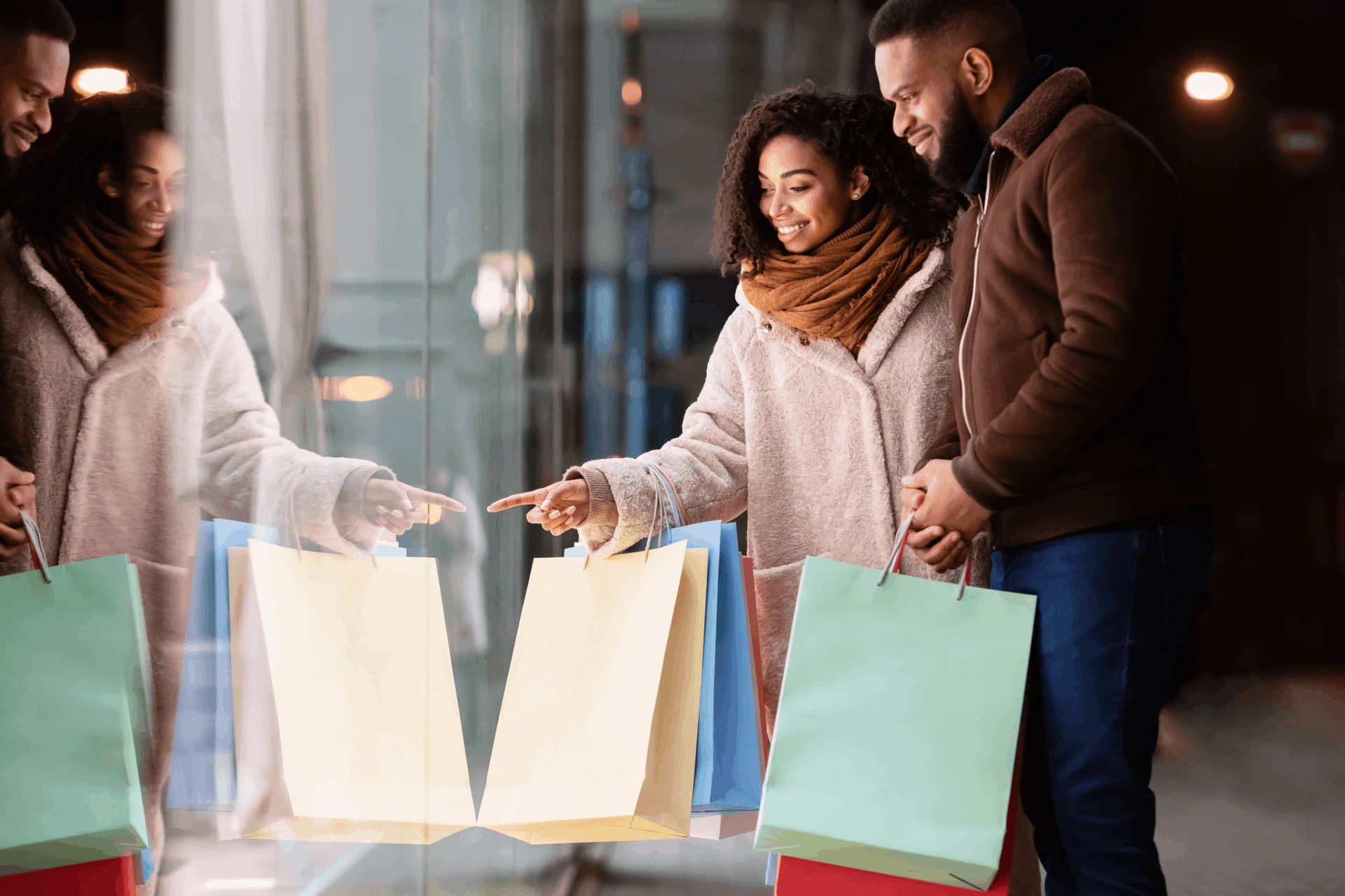 Couple admiring shopping bags outside a retail store window display.