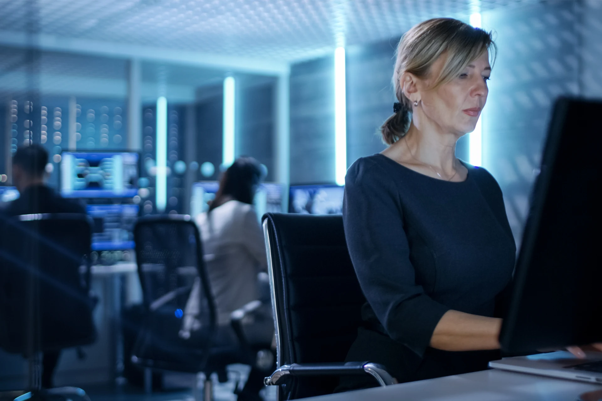 Professional working intently at a computer in a technology-focused space