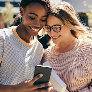 Two smiling teenagers looking at the Step mobile app on their phone