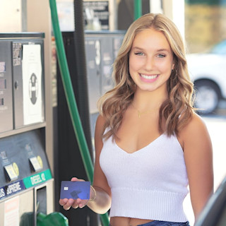Smiling girl at the gas station holding a Step Card