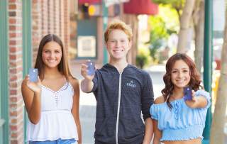 3 Teenagers holding up a Step Card smiling