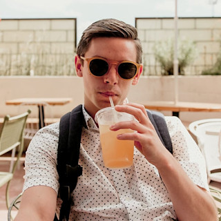Guy drinking a fountain drink wearing dark sunglasses while looking cool