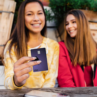 Two teenage girls smiling holding up a Step Card