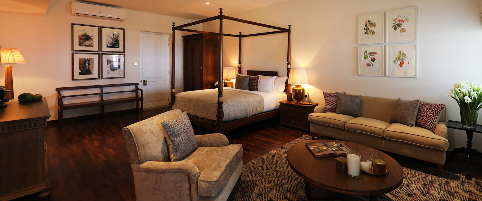 A Bungalow Suite with a dark four-poster bed, armchairs, a sofa and a round coffee table
