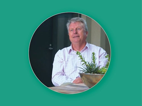 a man sitting at a table, image is in a circle with a green background