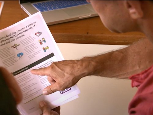 picture of two people looking at an NDIS prochure