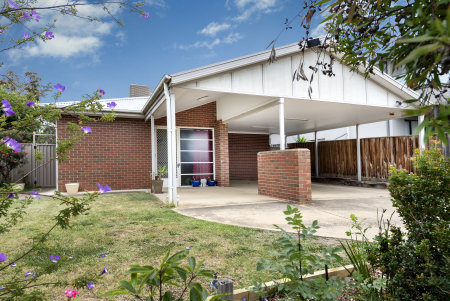 Image of a suburban house front, red brick house with concrete driveway and carport