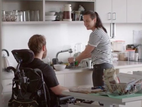 Person in a power chair in their kitchen with their support worker