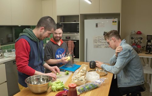 Three people in a kitchen preparing a meal