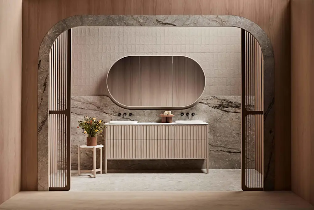 Elegant bathroom with marble walls, oval mirror above ribbed vanity cabinet, and small side table with flowers.