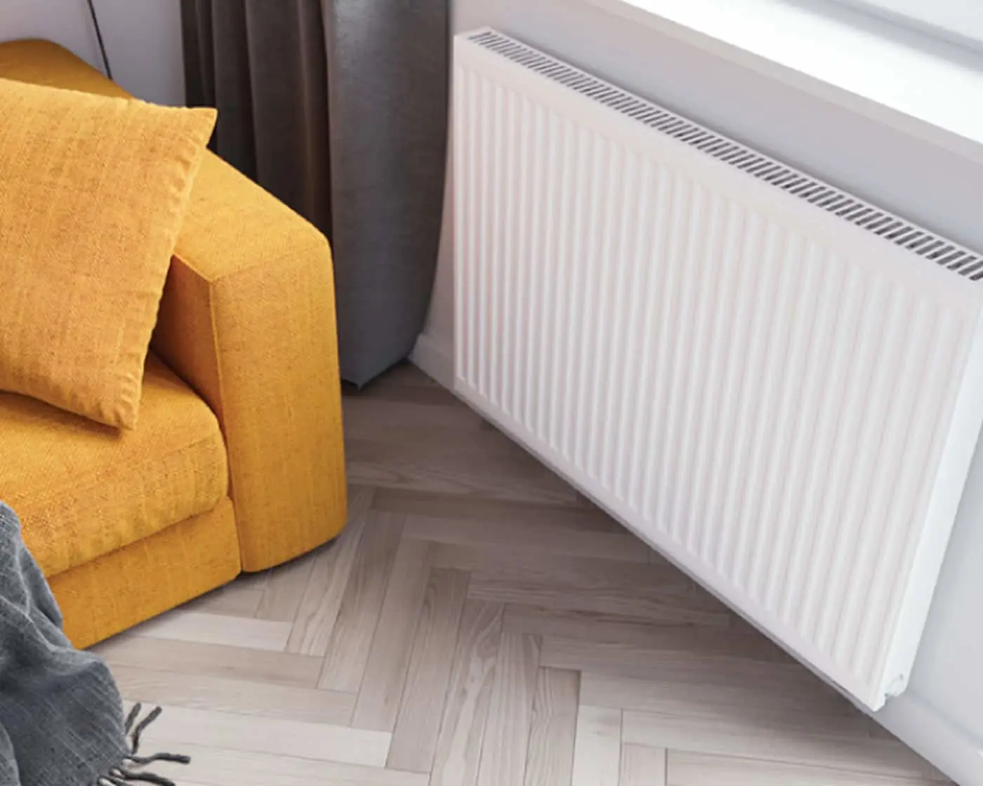 White wall-mounted radiator next to a yellow sofa with cushions on herringbone wooden flooring.